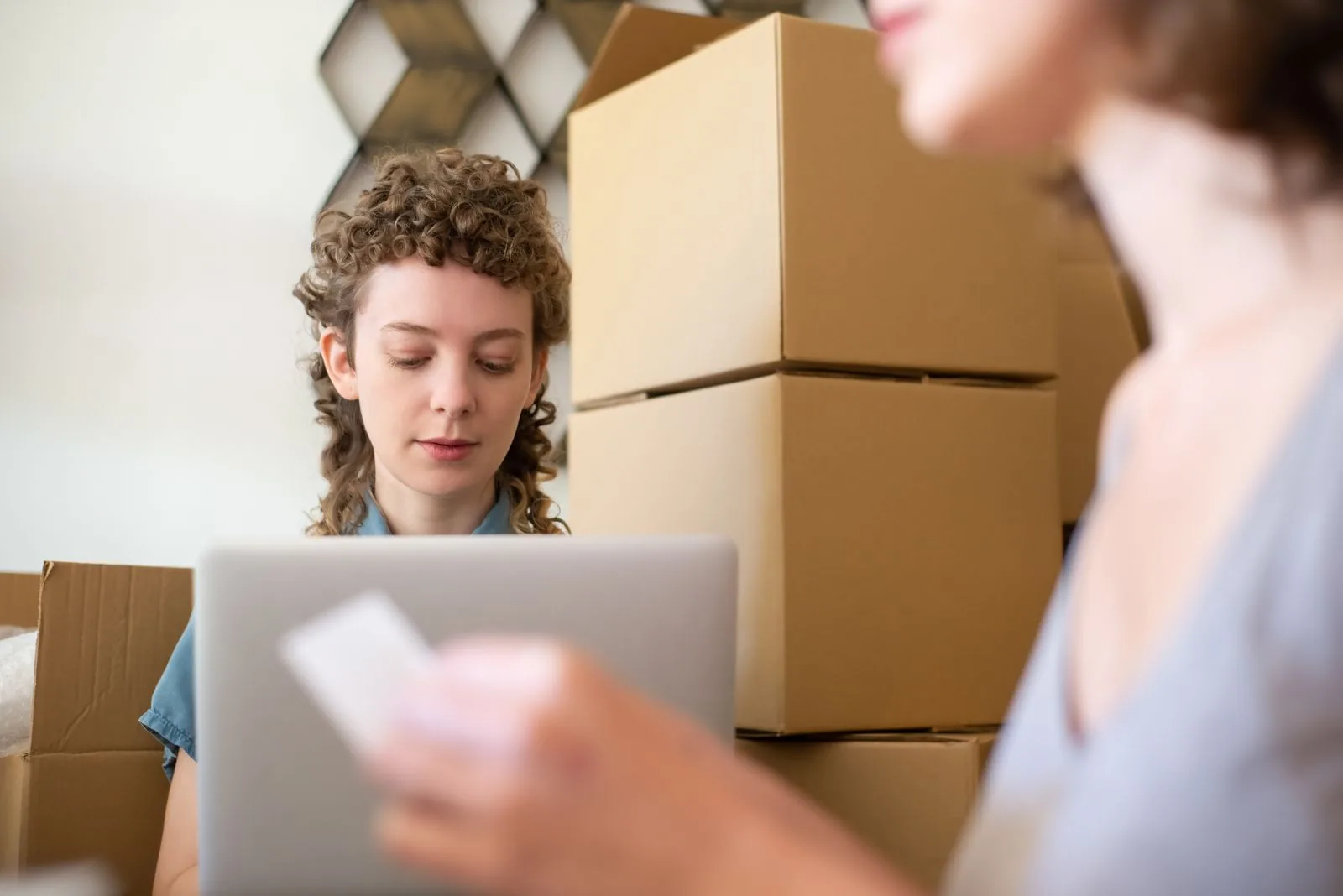 Small business owner packing online orders beside stacked boxes