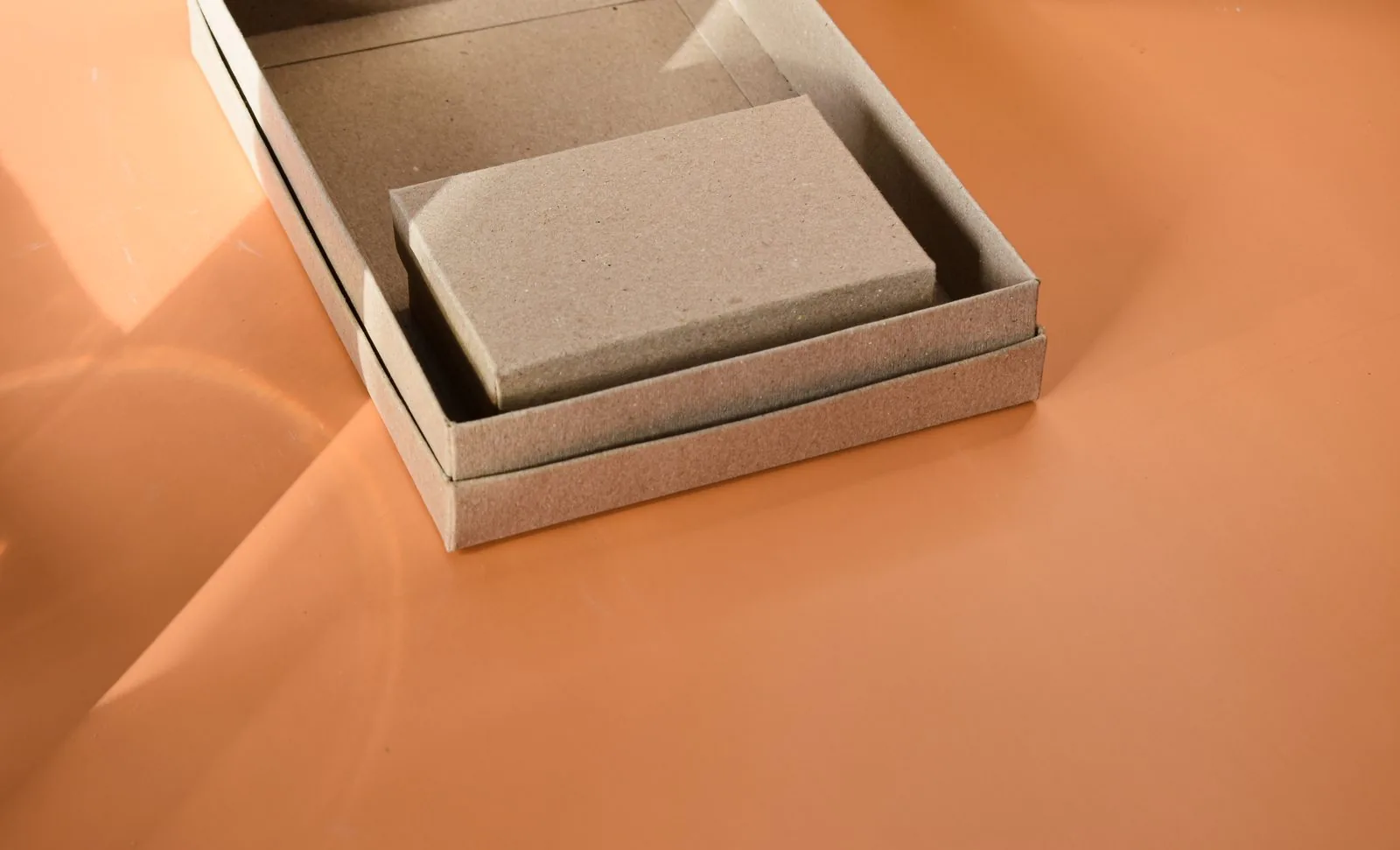 Kraft packaging boxes nested on an orange backdrop