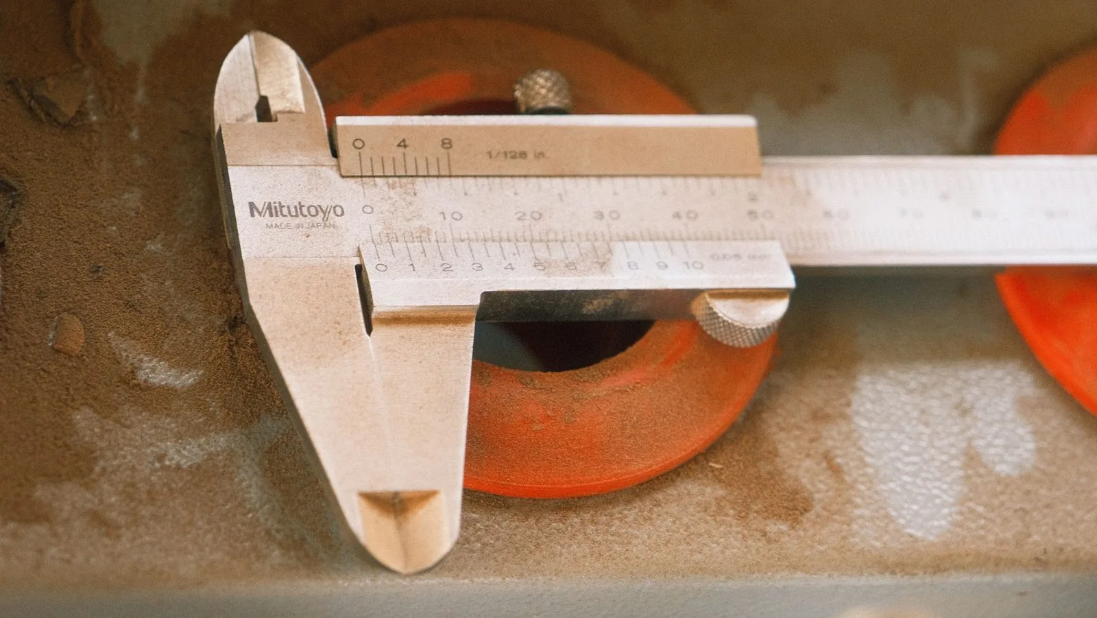 A caliper measuring an orange molded ring