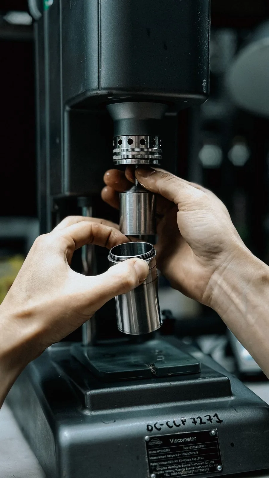 Hands adjusting a steel testing instrument in a laboratory