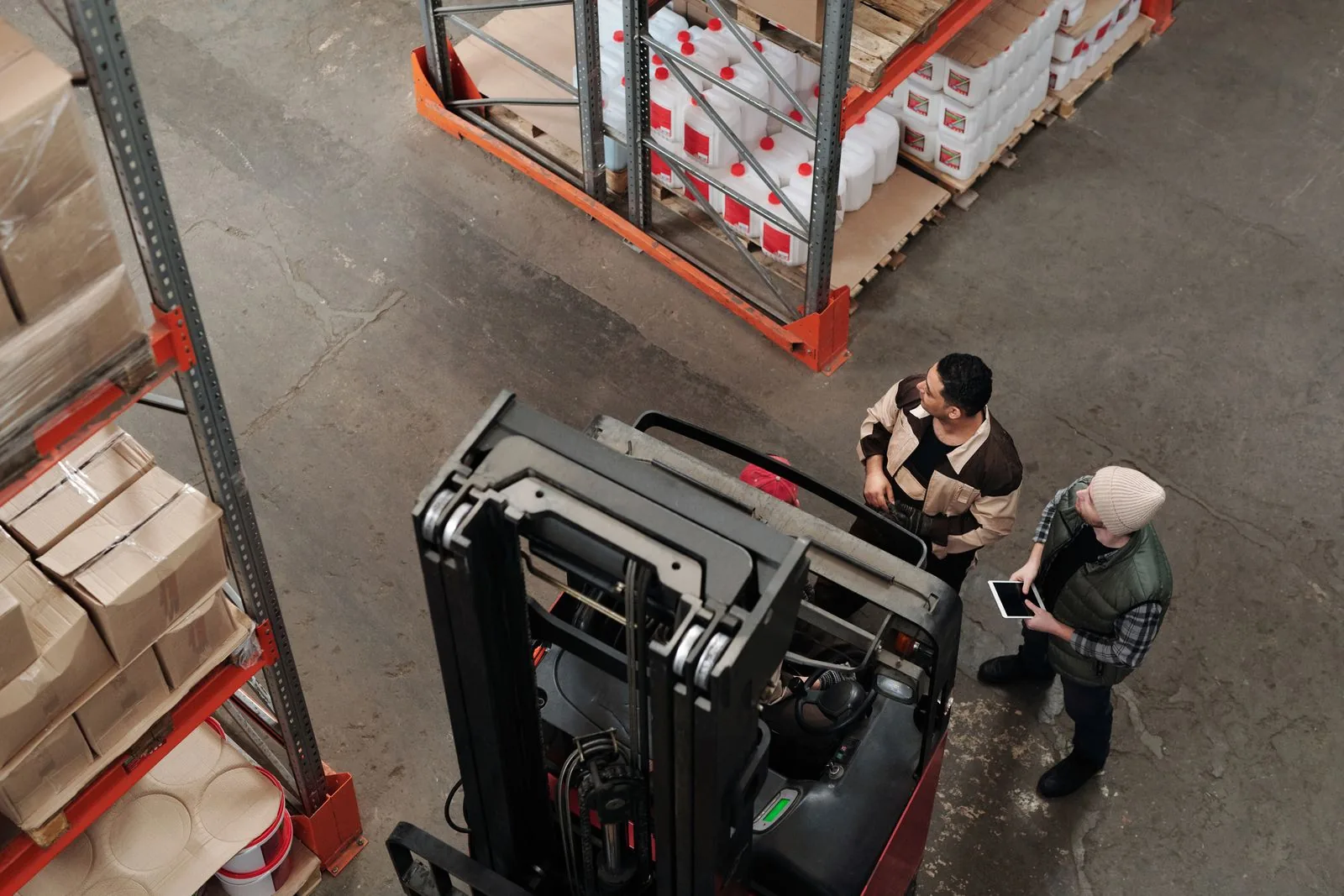 Two logistics specialists discussing an order next to a forklift